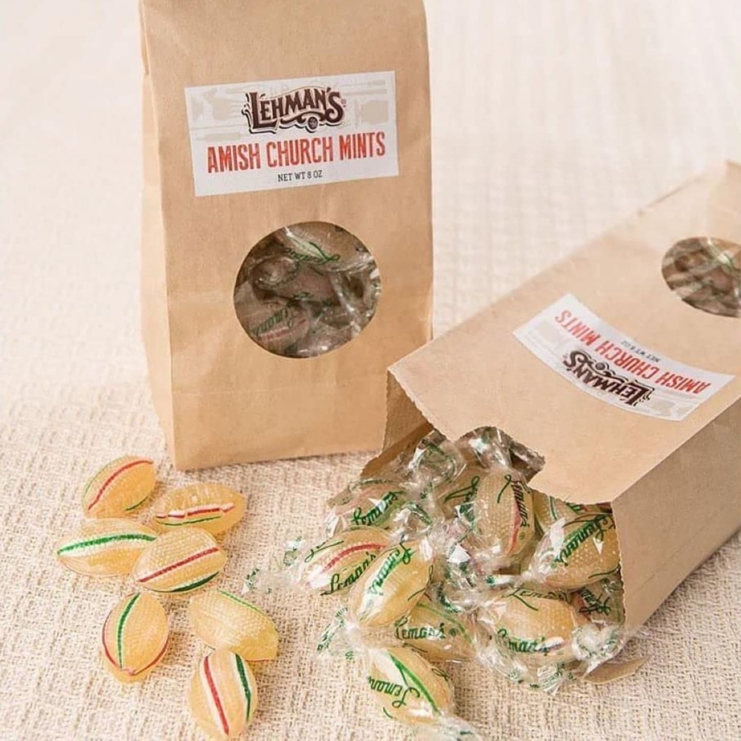 Brown paper bags of handcrafted Amish made hard mints with individually wrapped candies spilling out, featuring a cool peppermint flavor in USA made snacks and sweets collections.