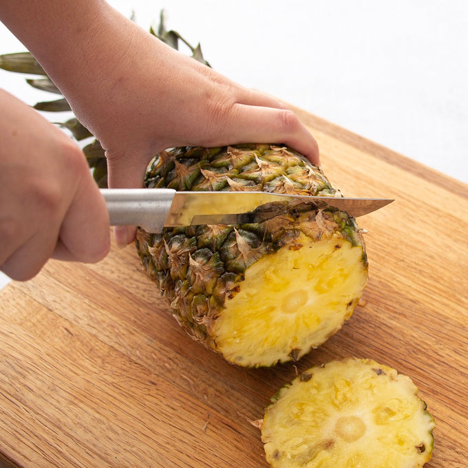 Handcrafted butcher knife with a silver brushed aluminum handle cutting a fresh pineapple on a wooden cutting board, ideal for Kitchen & Food, Food Prep, and USA Made collections.