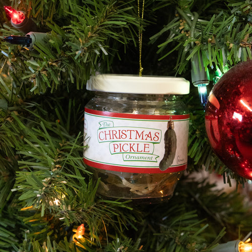 Glass jar ornament featuring a Christmas pickle replica hanging on a tree with gold string, embraced by holiday lights and traditional Christmas decor in Home & Decor.