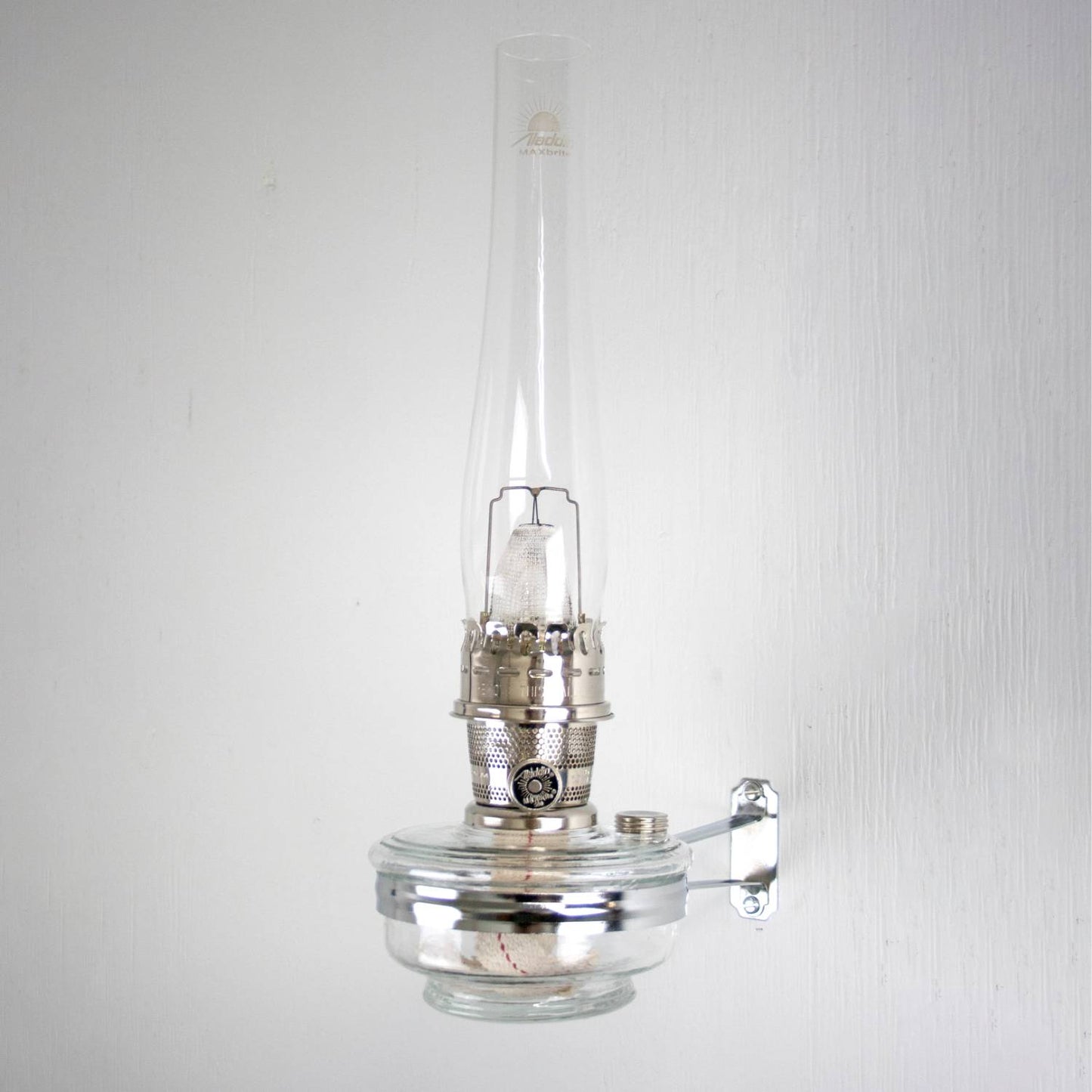 Clear glass oil lamp with tall chimney mounted on a shiny metal wall bracket, designed for use with classic Aladdin lamps in Lamps & Lighting, Oil Lamps, Wall Lamps, Best Sellers, and Promo Eligible collections.