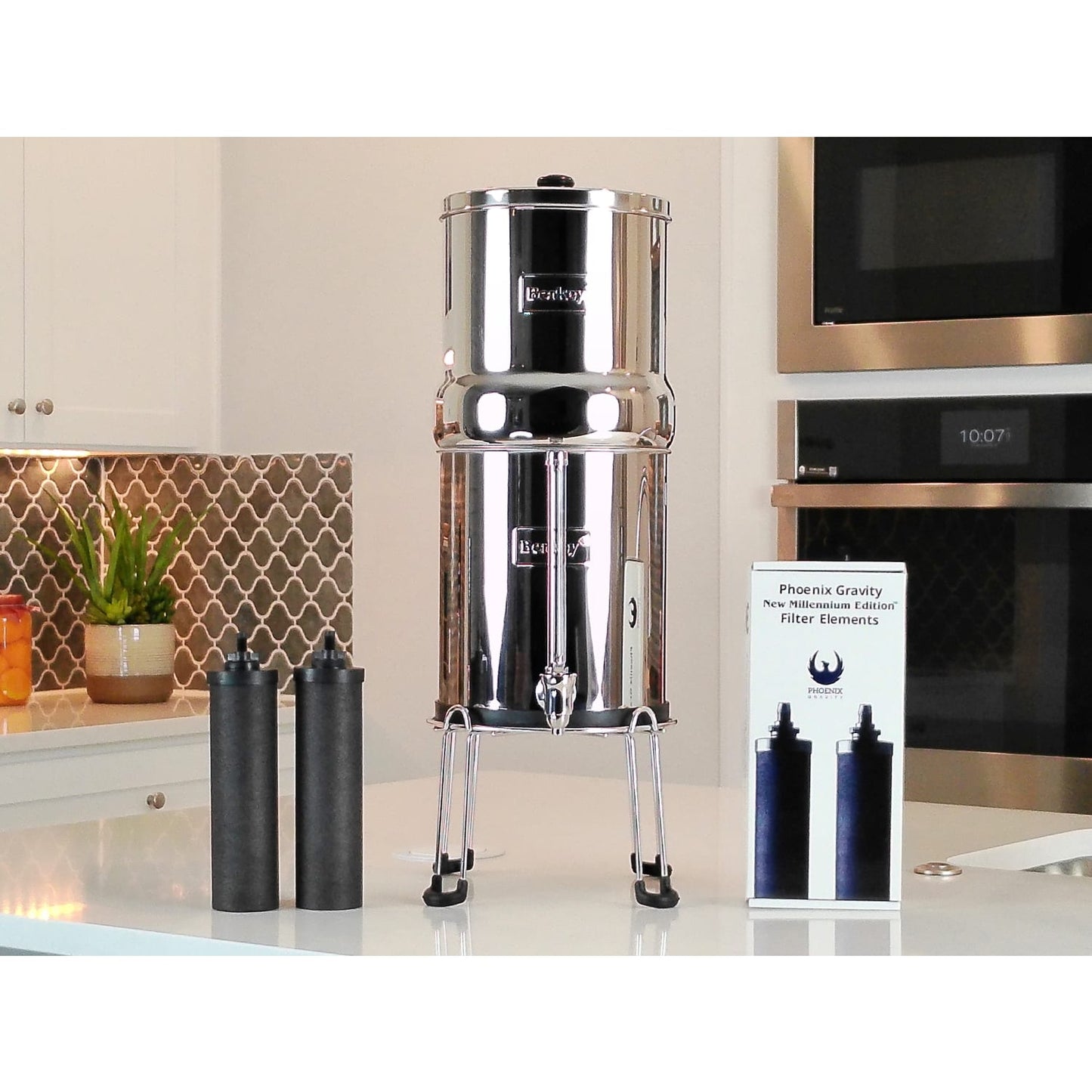 Pair of black synthetic water filter elements beside a polished stainless steel gravity water filter system on a kitchen counter, for Appliances, Water Heating and Treatment, Best Sellers, Promo Eligible, and Berkey Water Filters collections.