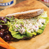 Hearty sandwich with creamy chicken salad, fresh lettuce, sprouts, and diced onions on rustic whole grain bread, served with grapes and carrots, ideal for Kitchen & Food, Food, Meats, Best Sellers, Promo Eligible collections.