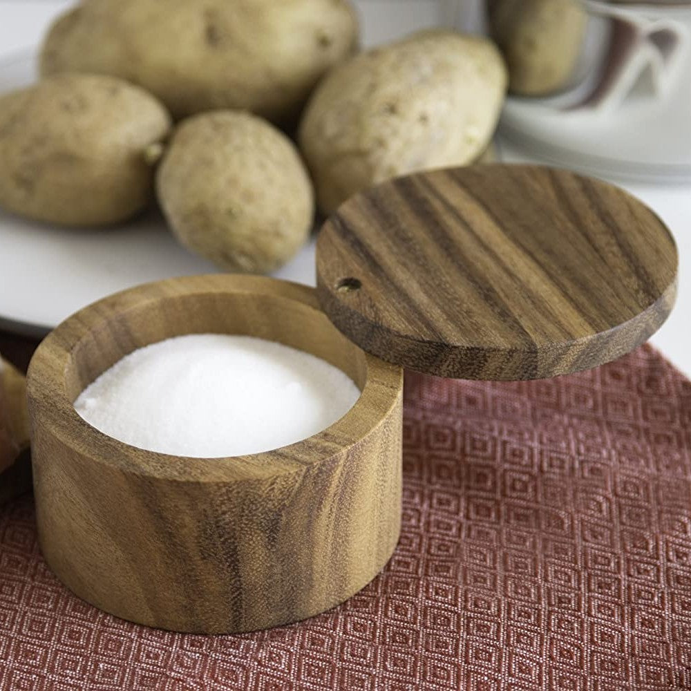 Handcrafted acacia wood salt cellar with a swivel lid designed to keep salt dry and accessible, shown on a dining setting with potatoes, ideal for Kitchen & Food and Storage and Serving collections.