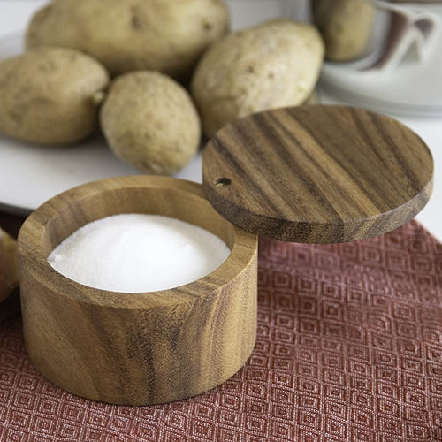 Handcrafted acacia wood salt cellar with a swivel lid designed to keep salt dry and accessible, shown on a dining setting with potatoes, ideal for Kitchen & Food and Storage and Serving collections.