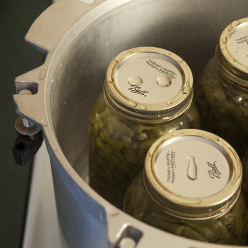 Close-up of glass canning jars filled with green beans inside a heavy-duty metal pressure canner, highlighting safe food preservation in Farm, Garden & Tool and Kitchen & Food collections.