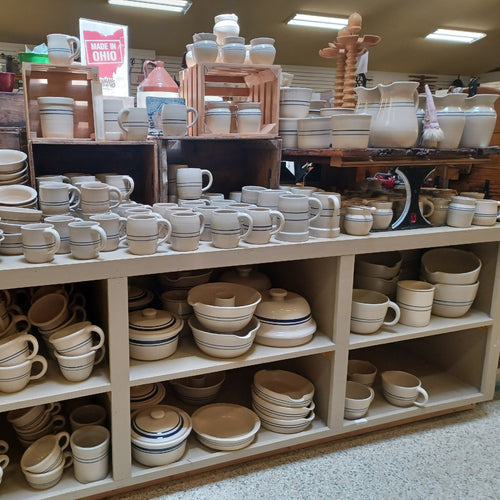 Shelves filled with handcrafted stoneware crocks, mugs, bowls, and pitchers in neutral tones, perfect for Kitchen & Food, Food Preservation, and USA Made collections.