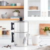 Stainless steel non-electric drip coffee maker with black handles on a white kitchen countertop, surrounded by coffee beans, a white mug, and a spoon, featured in Farm, Garden & Tool and Kitchen & Food collections.