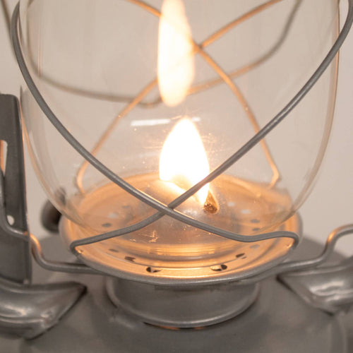 Close-up of a handcrafted metal lantern’s glass globe and flame protected by a sturdy wire frame, ideal for reliable lighting in farm, garden, camping, and emergency use.