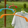 Set of four brightly colored adjustable plastic hangers with swivel hooks and drying holes hanging outdoors on clotheslines with a white shirt, ideal for Home & Decor and Laundry Supplies collections.