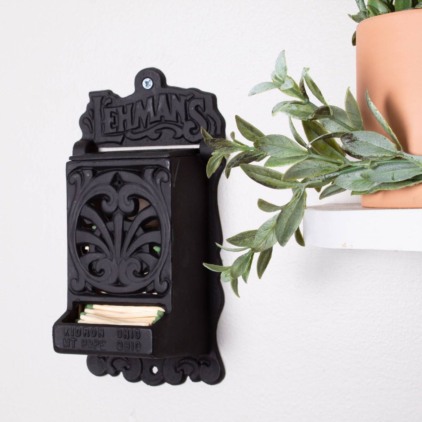 Handcrafted black cast iron wall-mounted matchbox holder with decorative vintage cutout design and Lehman's embossed branding, Amish made in USA, featured in Home & Decor, Household Helpers, and Best Sellers collections.