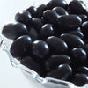 Close-up of large smooth black licorice jelly beans piled in a clear glass bowl, featured in Kitchen & Food, Snacks and Sweets, and Best Sellers collections.