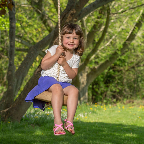 Young girl smiling while sitting on a handcrafted round wooden swing hanging from a tree outdoors, part of Toys, Books & Games, USA Made, Children's Toys, and Outdoor Play collections.