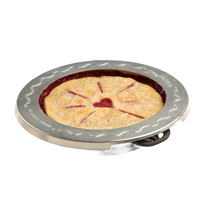 Aluminum pie crust shield placed around the edges of a golden brown pie with decorative slits and a heart-shaped center cutout, protecting the crust from burning during baking.