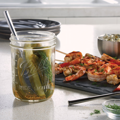 Clear handcrafted wide-mouth pint jar made in USA, filled with pickled vegetables, shown with metal spoon on kitchen counter near grilled shrimp skewers, highlighting Kitchen & Food, Food Preservation, and Canning collections.