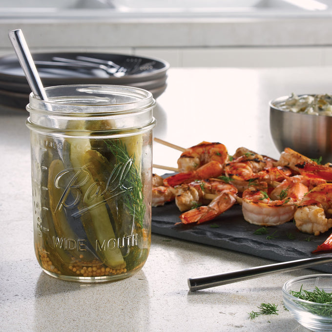 Clear handcrafted wide-mouth pint jar made in USA, filled with pickled vegetables, shown with metal spoon on kitchen counter near grilled shrimp skewers, highlighting Kitchen & Food, Food Preservation, and Canning collections.