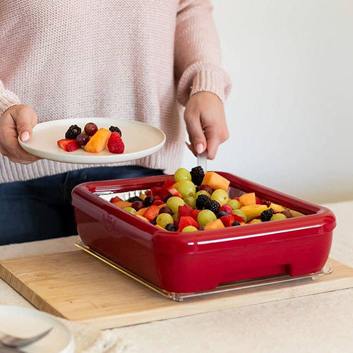 Person serving assorted fresh fruit from a vibrant red rectangular ceramic dish placed on a wooden board, ideal for Kitchen & Food, Kitchen Accessories, and Storage and Serving collections.