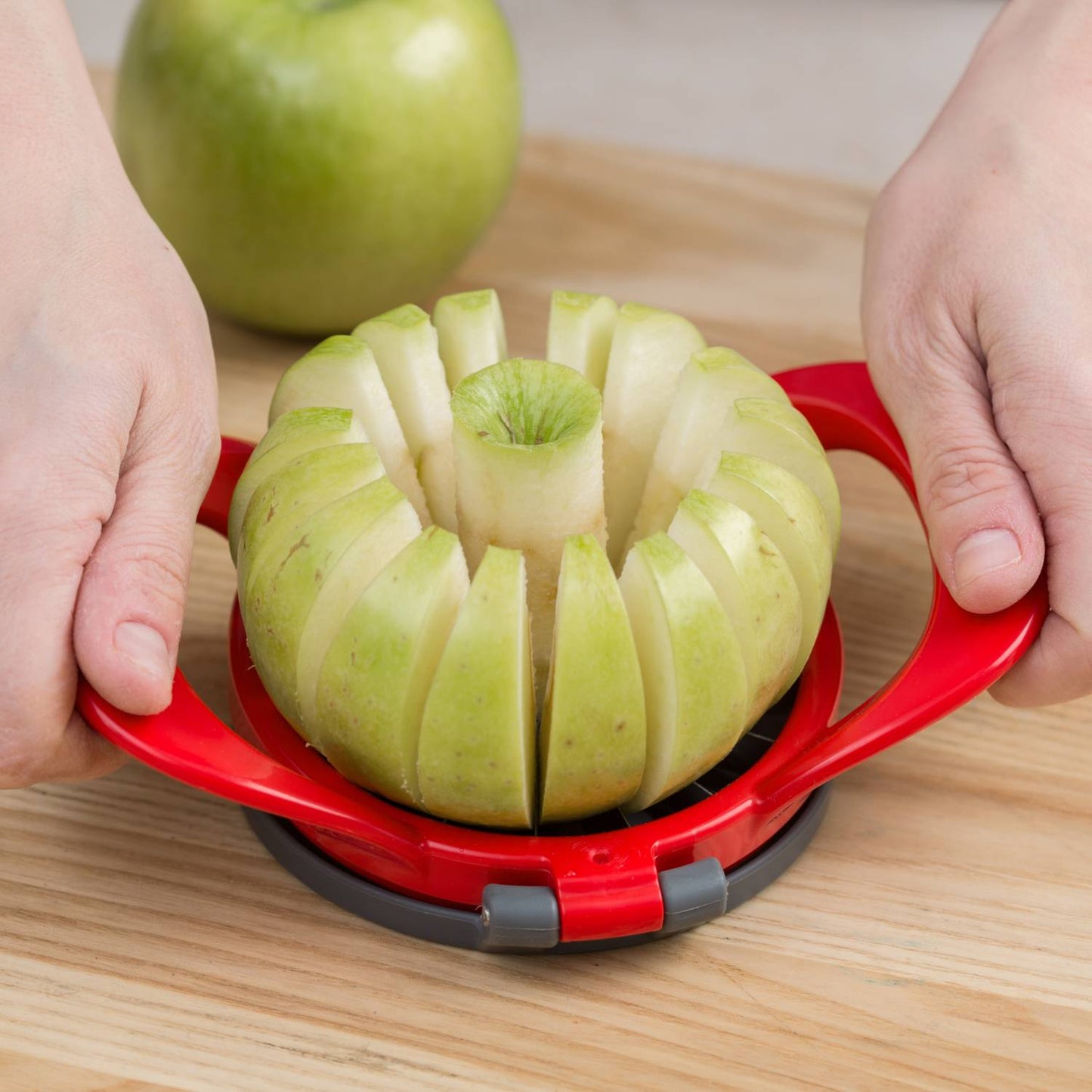 Hard plastic apple slicer with stainless steel blades cutting a green apple into sixteen thin, uniform wedges, ideal for baking and snacking in kitchen and garden tool collections.