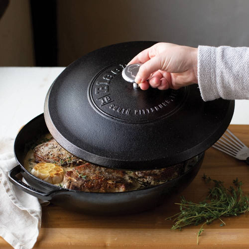 Handcrafted Lodge Blacklock cast iron braiser with secure lid lifting to reveal seared pork chops and roasted garlic, ideal for Kitchen & Food, Cookware, Cast Iron, USA Made collections.