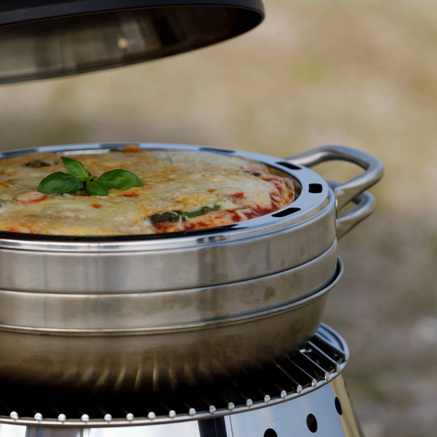 Close-up of a handcrafted stainless steel camping oven baking a golden casserole topped with fresh basil, designed for outdoor use in Farm, Garden & Tool and Camping collections.