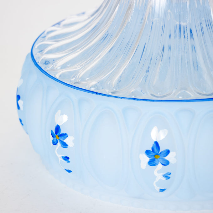 Close-up of a pale blue glass lamp shade with delicate hand-painted blue and white floral accents, designed to soften and diffuse light, featured in Lamps & Lighting and Best Sellers.