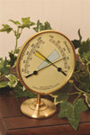 Brass hygrometer and thermometer with dual dials measuring temperature in Fahrenheit and Celsius and relative humidity, displayed on a round stand amid green ivy, ideal for Home & Decor and Household Helpers collections.