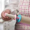 Person adjusting removable pink and blue thickness discs on a beechwood adjustable rolling pin, part of kitchen gadgets and baking supplies for precise dough preparation.