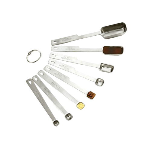 Set of eight stainless steel measuring spoons with deep elongated bowls, including smidgen, pinch, and dash sizes, designed for precise kitchen measuring in baking and food prep collections.