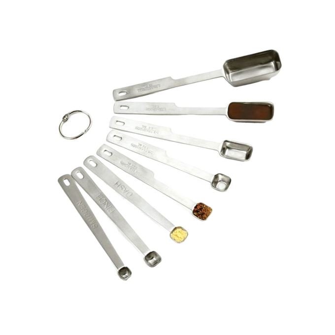 Set of eight stainless steel measuring spoons with deep elongated bowls, including smidgen, pinch, and dash sizes, designed for precise kitchen measuring in baking and food prep collections.