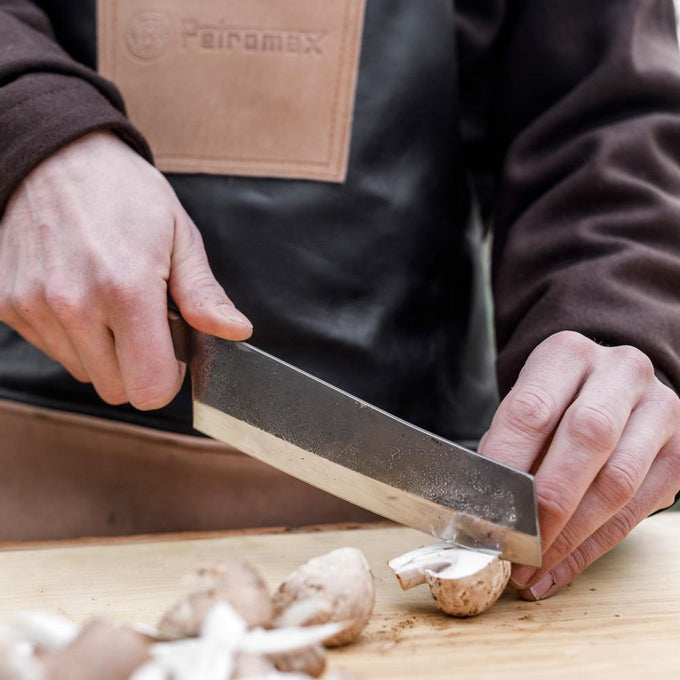 Close-up of a handcraft outdoor chef’s knife with a sharp high-quality steel blade and robust walnut handle slicing fresh mushrooms, ideal for Farm, Garden & Tool and Camping collections.