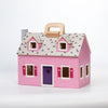 Pink wooden foldable dollhouse with purple door, gray shingled roof, and wooden handle, featuring small cutout windows with red shutters, designed for children's indoor play collections.
