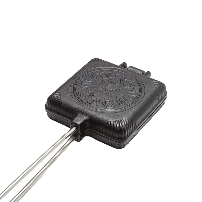 Cast iron sandwich iron with a hinged design and decorative embossed lid, suited for toasting sandwiches over campfires, featured in Farm, Garden & Tool and Camping collections.