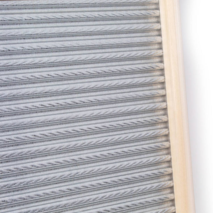 Handcrafted galvanized metal washboard with spiral crimp design and light wooden frame, designed for effective stain removal in laundry supplies, made in USA.