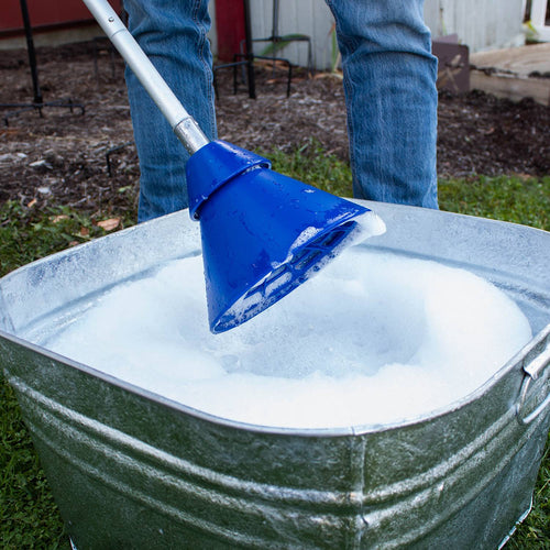 Metal tub filled with soapy water being used with a blue hand-operated collapsible washer plunger on grass outdoors, ideal for Home & Decor and Laundry Supplies collections.