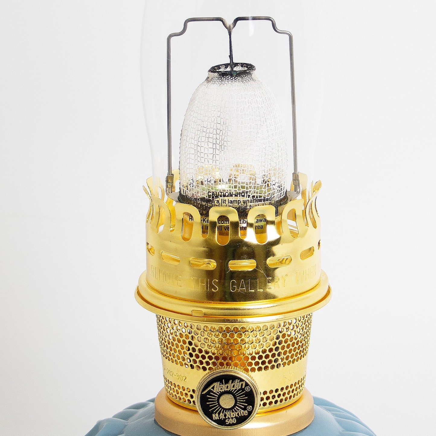 Close-up of a handcrafted brass burner with perforated design and textured glass chimney on a limited edition Georgia Blue glass base oil lamp, featured in Lamps & Lighting, Oil Lamps, Table Lamps, Best Sellers, and Promo Eligible collections.