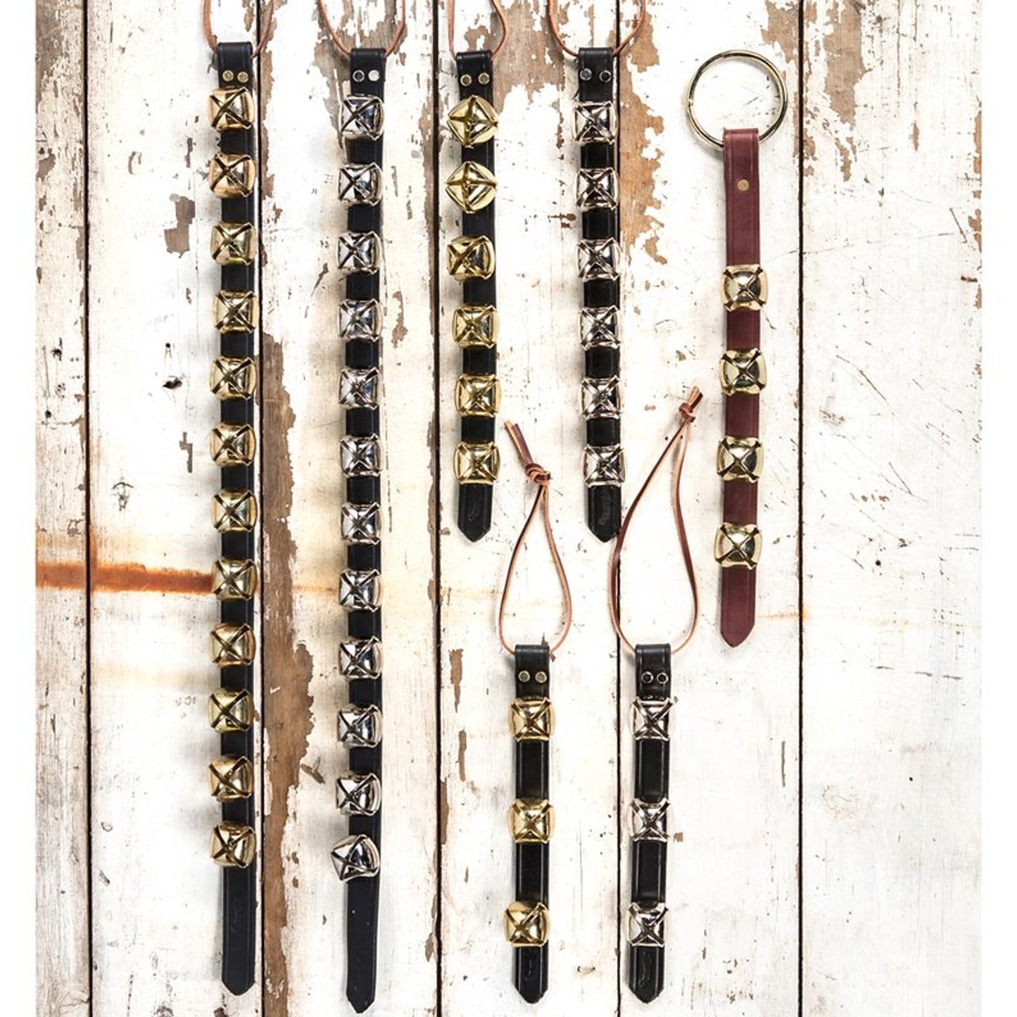 Assortment of handcrafted sleigh bell door hangers with brass and silver bells mounted on black and brown leather straps, perfect for holiday decor, USA made, best sellers.
