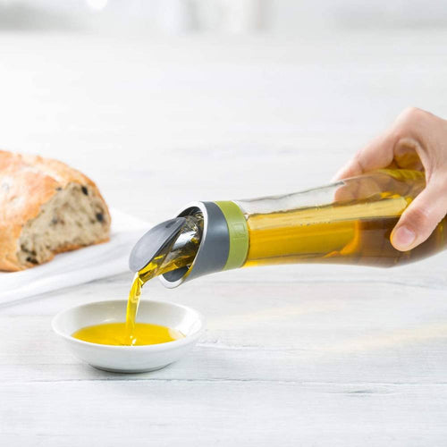 Glass oil bottle with automatic flip-top pour spout dispensing golden oil into a small white dish, designed for mess-free use in Kitchen & Food, Cookware, and Kitchen Gadgets collections.