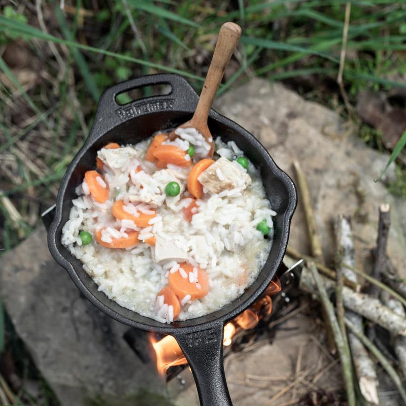 Heavy-duty cast iron skillet with long handle cooking a creamy rice dish with carrots, peas, and chicken over an open campfire, ideal for Farm, Garden & Tool, Kitchen & Food, Camping, Cookware, Cast Iron, Best Sellers, and Promo Eligible collections.
