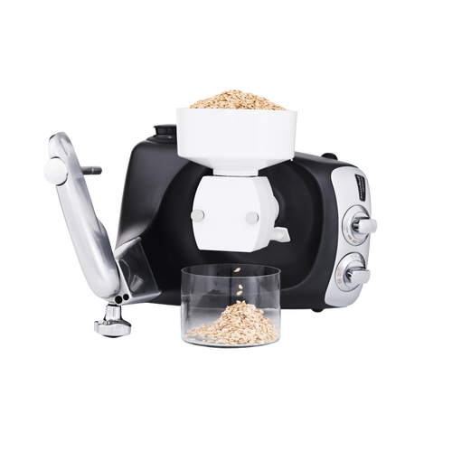 Black and silver stand mixer fitted with a white flake mill attachment rolling oats into flakes collected in a clear container, ideal for Kitchen & Food, Baking Supplies, Grain Mills, and Promo Eligible collections.