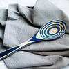 Handcrafted pakkawood spoon with bold blue and natural wood concentric rings, resting on textured gray fabric, ideal for Kitchen & Food, Kitchen Gadgets, Cooking and Baking Helpers collections.