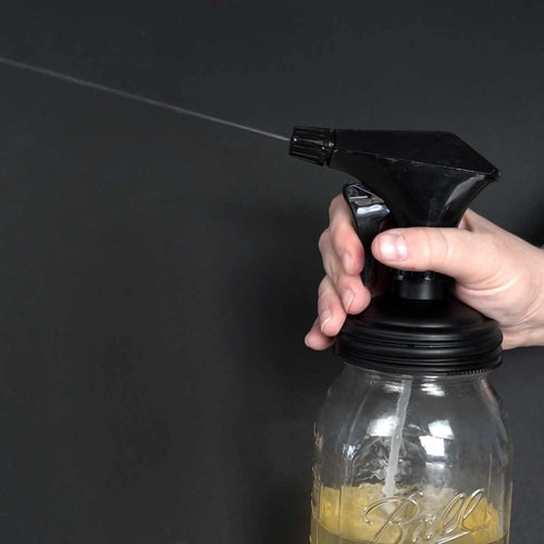 Hand pressing black sprayer lid dispensing liquid from glass jar, part of eco-friendly Household Helpers, Home & Decor, USA Made, and Best Sellers collections.