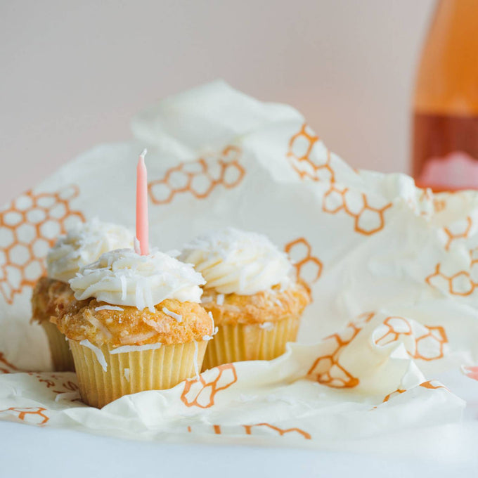 Handmade large beeswax food wrap featuring orange honeycomb pattern on cream muslin, shown with cupcakes and birthday candle, part of Kitchen & Food, Storage and Serving, USA Made, and Best Sellers collections.