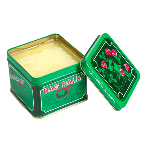 Open green metal tin of Bag Balm with creamy yellow balm inside, featuring vintage-style labeling with red flowers and leaf design, ideal for Health & Wellness and USA Made collections