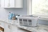 White plastic laundry basket with blue grip handles and ventilated sides for airflow, designed for comfortable carrying and home laundry organization, made in USA.