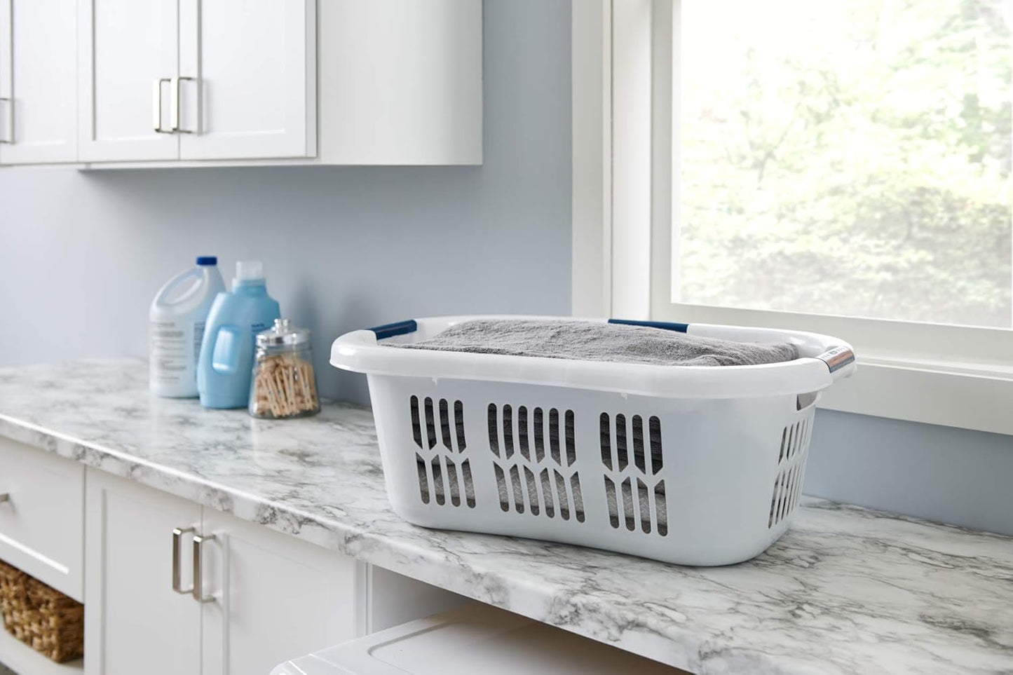 White plastic laundry basket with blue grip handles and ventilated sides for airflow, designed for comfortable carrying and home laundry organization, made in USA.