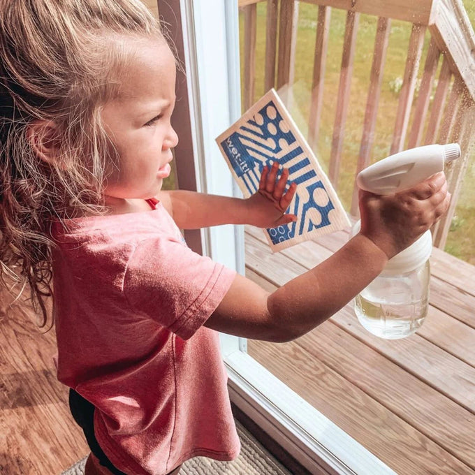 Child using a clear regular-mouth glass jar with a white sprayer lid to clean a window, demonstrating eco-friendly home cleaning tools from Home & Decor, Household Helpers, USA Made collections.