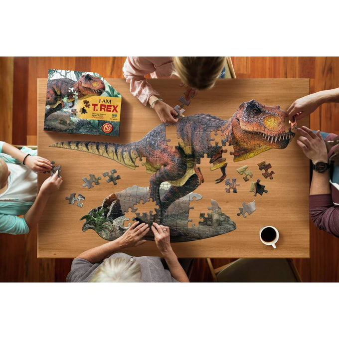Four people assembling a unique dinosaur-shaped 100-piece puzzle featuring a detailed T-Rex illustration, part of Toys, Children's Toys, Games and Puzzles, and Best Sellers collections.