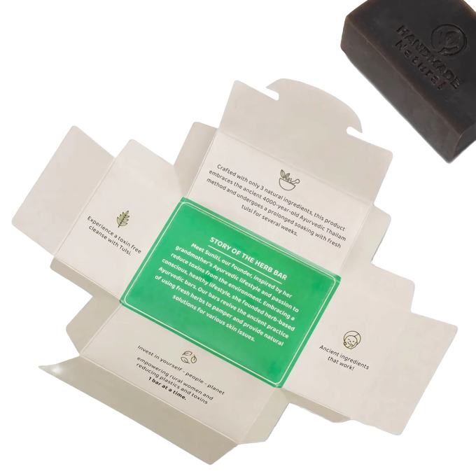 Opened packaging displaying the story and benefits of the handcrafted Tulsi Clarifying Ayurvedic Bar Soap with a dark brown bar featuring a “Handmade” impression, ideal for health and wellness and soapmaking collections.