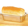 Shiny stainless steel loaf pan holding freshly baked golden bread, suitable for kitchens, baking supplies, and homesteading collections, featuring durable rust-resistant construction.