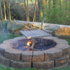 Outdoor stone fire pit with a sturdy metal grilling grate and adjustable support post, designed for durable campfire cooking in Farm, Garden & Tool, Camping, and Grilling collections.