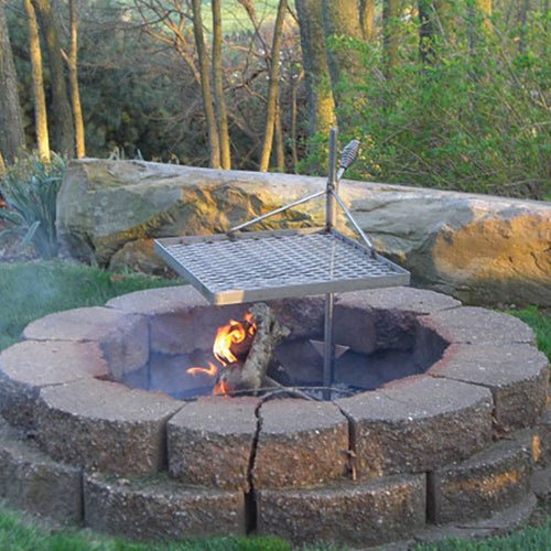 Outdoor stone fire pit with a sturdy metal grilling grate and adjustable support post, designed for durable campfire cooking in Farm, Garden & Tool, Camping, and Grilling collections.